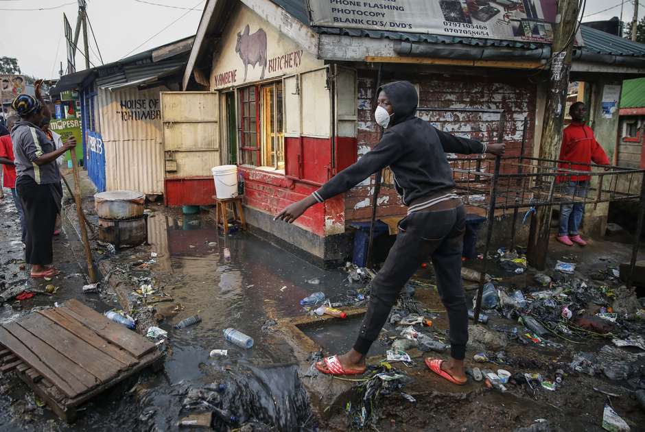A boy wearing a mask as protection from coronavirus picks his way through a flooded slum in Nairobi, Kenya. (Brian Inganga, AP)