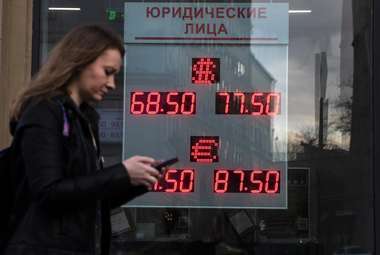 A woman walks past an currency exchange office screen displaying the exchange rates of U.S. dollar and euro to Russian rubles, in Moscow, Russia. (AP Photo/Pavel Golovkin)