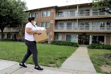 A woman walks with a box of produce she received during a food drive. (AP Photo/Julio Cortez)