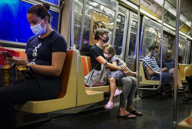 New York City subway passengers wear protective masks because of COVID-19 concerns. (AP Photo/John Minchillo)